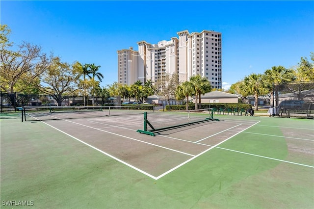 view of tennis court featuring a city view and fence