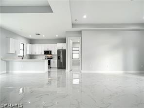 kitchen with appliances with stainless steel finishes, light tile patterned flooring, and white cabinets