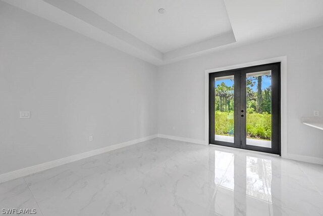 spare room with a raised ceiling and french doors