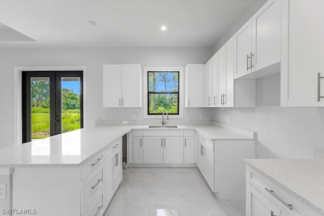 kitchen featuring white cabinetry, sink, light stone counters, and french doors