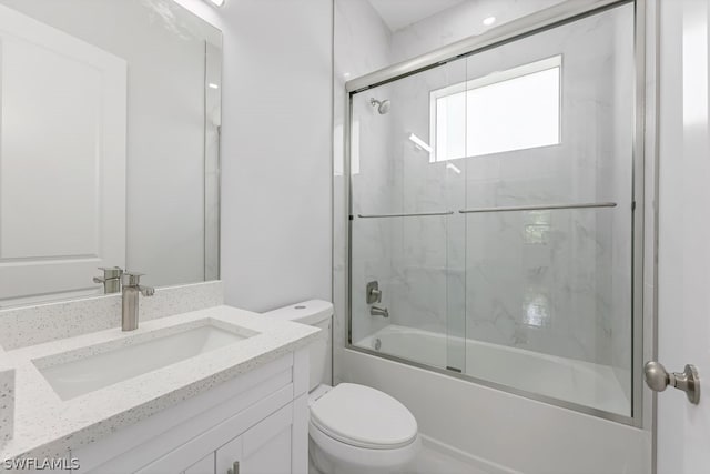 full bathroom with bath / shower combo with glass door, vanity, and toilet