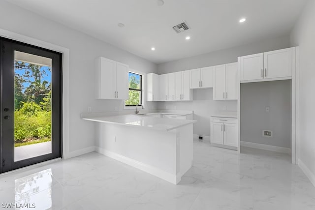 kitchen featuring kitchen peninsula, sink, and white cabinets