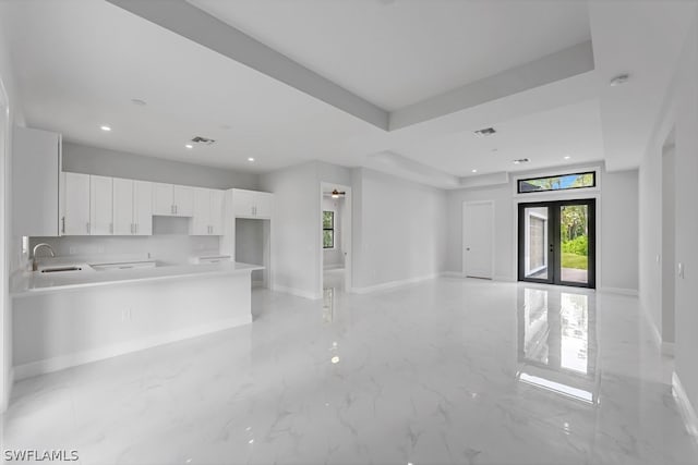 kitchen with white cabinetry, sink, decorative backsplash, a raised ceiling, and french doors