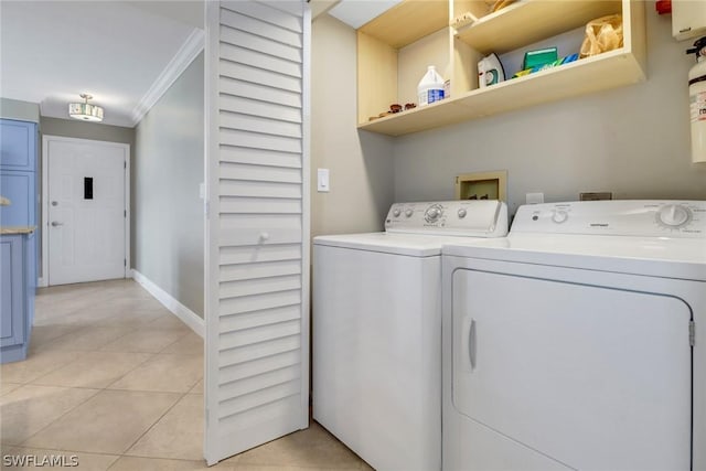 clothes washing area with ornamental molding, washing machine and dryer, and light tile patterned floors