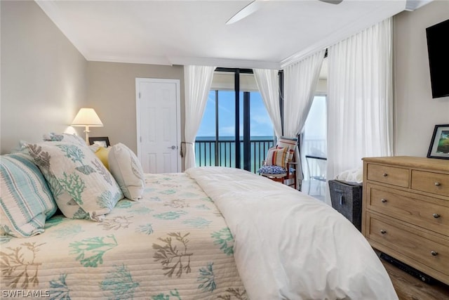 bedroom with hardwood / wood-style flooring, ceiling fan, access to exterior, a water view, and ornamental molding