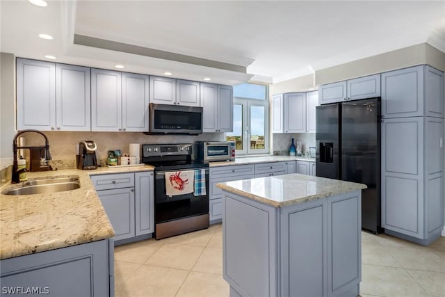 kitchen featuring a kitchen island, appliances with stainless steel finishes, tasteful backsplash, sink, and light stone counters