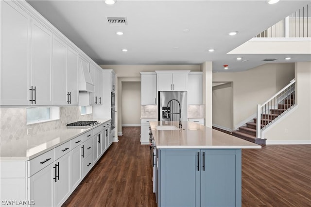 kitchen featuring sink, appliances with stainless steel finishes, an island with sink, white cabinets, and dark hardwood / wood-style flooring