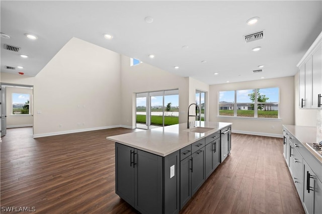 kitchen with dark hardwood / wood-style floors, stainless steel dishwasher, sink, an island with sink, and white cabinets