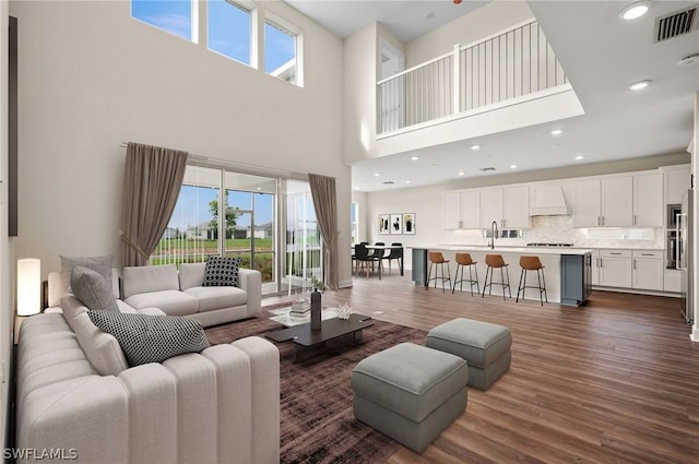 living room with dark wood-type flooring, a high ceiling, and sink