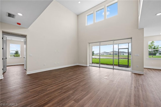 unfurnished living room featuring high vaulted ceiling and dark wood-type flooring