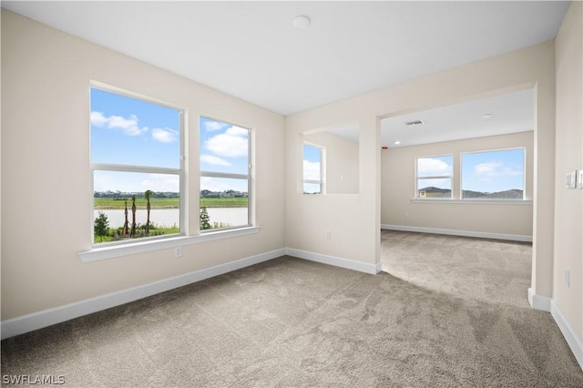 spare room featuring light colored carpet and a water view