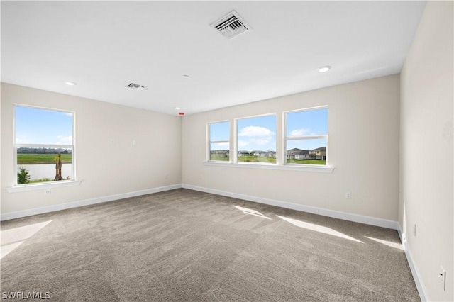 unfurnished room with light colored carpet and a water view