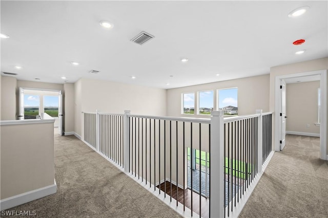 hallway featuring light carpet and a healthy amount of sunlight