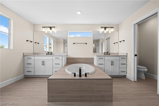 bathroom featuring tiled bath, tile patterned flooring, vanity, and a healthy amount of sunlight