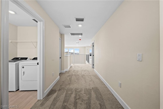 hallway featuring light colored carpet and washing machine and dryer