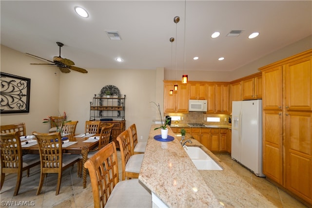 kitchen with white appliances, light tile patterned floors, ceiling fan, light stone countertops, and hanging light fixtures