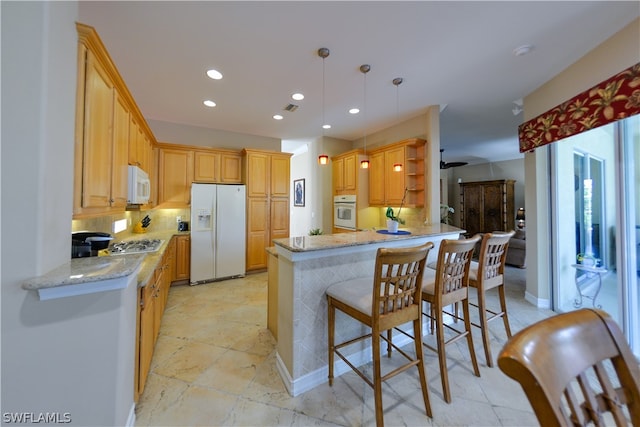 kitchen with white appliances, light stone counters, kitchen peninsula, backsplash, and decorative light fixtures