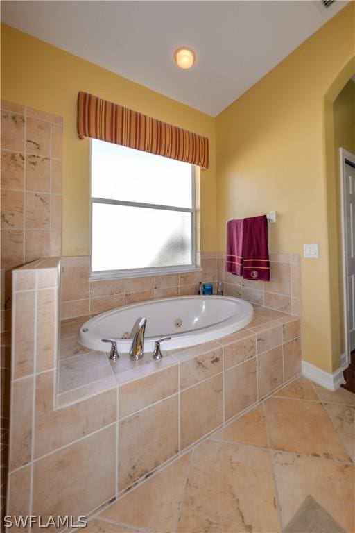 bathroom with a relaxing tiled tub and tile patterned floors