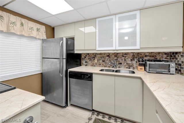 kitchen with appliances with stainless steel finishes, a drop ceiling, sink, and tasteful backsplash