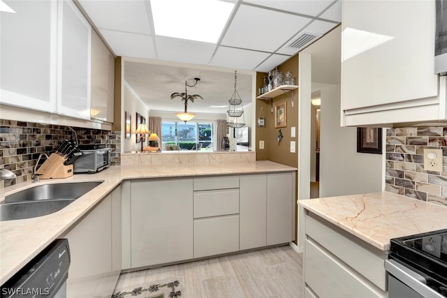 kitchen with white cabinets, hanging light fixtures, stainless steel dishwasher, a paneled ceiling, and decorative backsplash