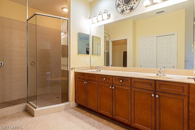 bathroom with double vanity, an enclosed shower, and tile patterned flooring