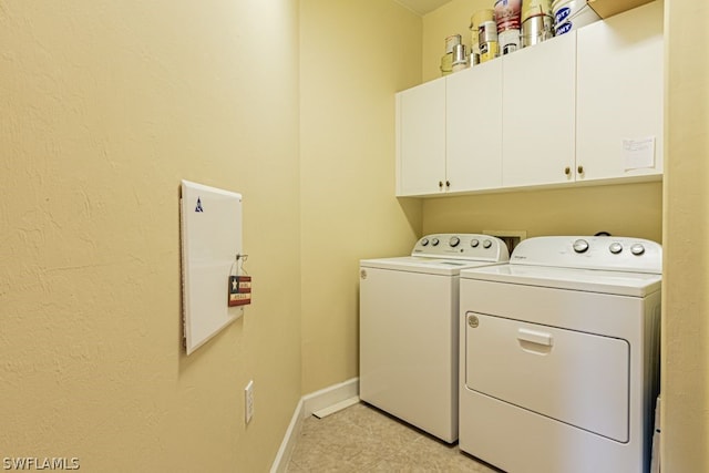 clothes washing area featuring light tile patterned flooring, washer and dryer, and cabinets