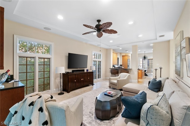 living room with a tray ceiling and ceiling fan