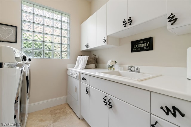 clothes washing area with sink, washer and clothes dryer, and cabinets