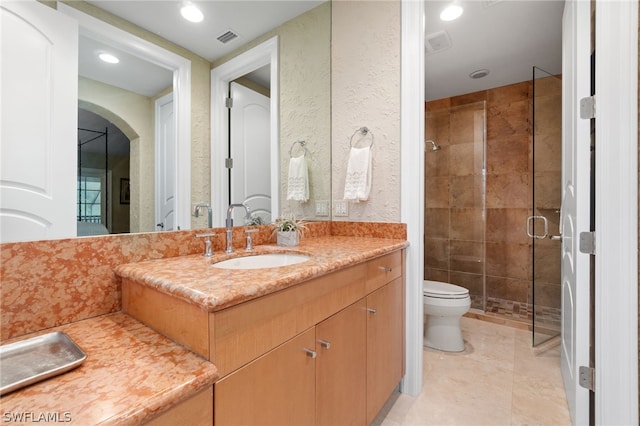 bathroom featuring vanity, a shower with shower door, and toilet