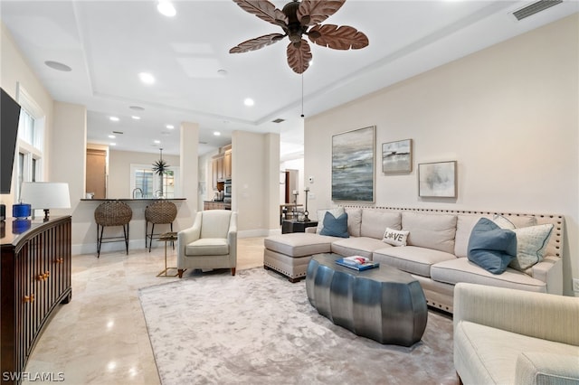 living room featuring a tray ceiling and ceiling fan