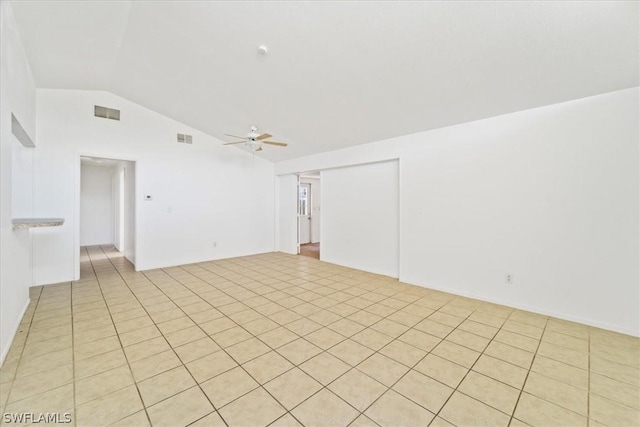 empty room with ceiling fan, light tile patterned flooring, and vaulted ceiling