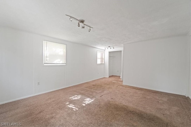 carpeted empty room with a textured ceiling and track lighting