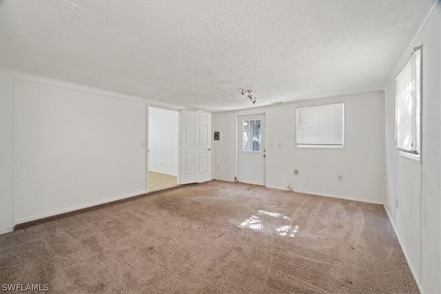 empty room featuring carpet, a textured ceiling, and a healthy amount of sunlight