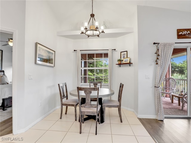 dining space featuring high vaulted ceiling, light wood-type flooring, and ceiling fan with notable chandelier