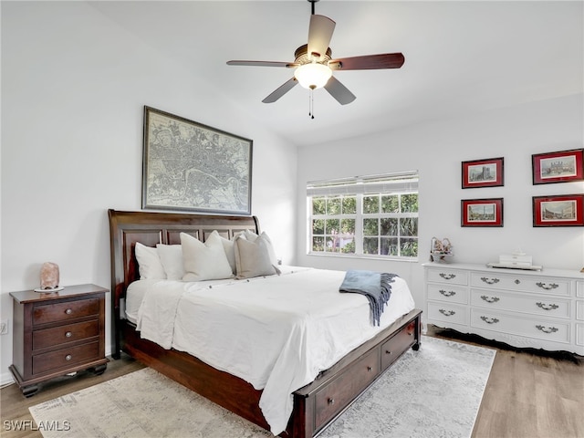 bedroom featuring light hardwood / wood-style floors, vaulted ceiling, and ceiling fan