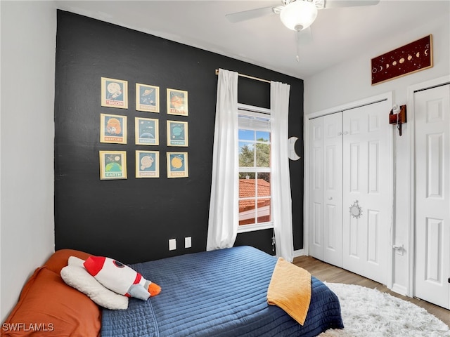 bedroom with two closets, ceiling fan, and hardwood / wood-style floors