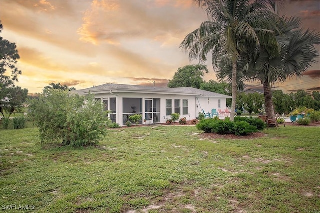 back house at dusk with a lawn