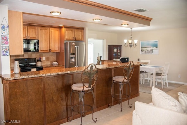 kitchen with kitchen peninsula, black appliances, and decorative light fixtures