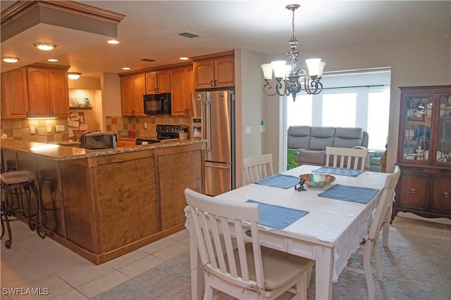 kitchen featuring an inviting chandelier, backsplash, pendant lighting, light tile patterned flooring, and black appliances