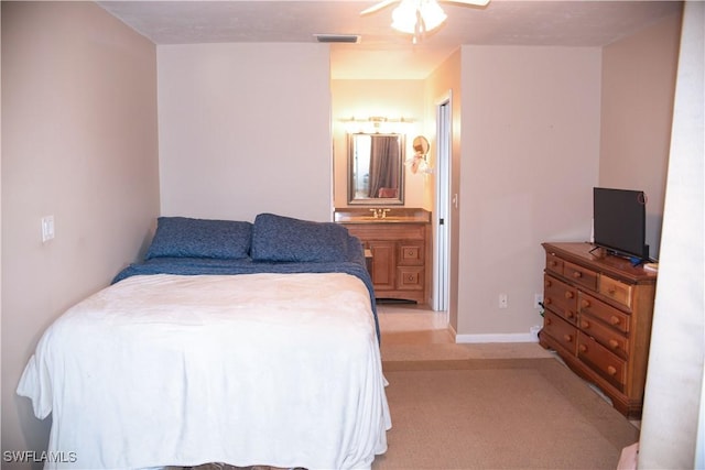 bedroom with light carpet, ensuite bathroom, and ceiling fan