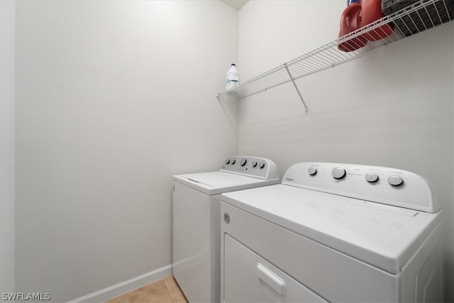 laundry area featuring washer and dryer, laundry area, light tile patterned flooring, and baseboards