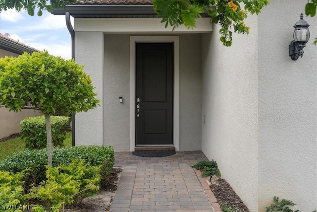 doorway to property featuring a tile roof and stucco siding