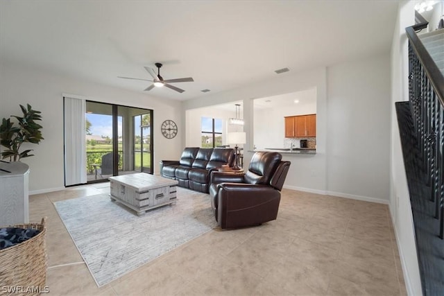 living room with a ceiling fan, baseboards, and light tile patterned floors