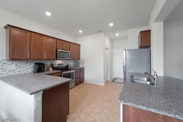 kitchen featuring stainless steel appliances, visible vents, decorative backsplash, a sink, and a peninsula