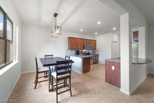 kitchen featuring tasteful backsplash, baseboards, appliances with stainless steel finishes, brown cabinets, and recessed lighting