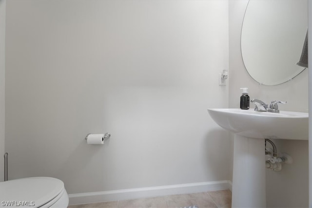 bathroom with tile patterned flooring, baseboards, and toilet