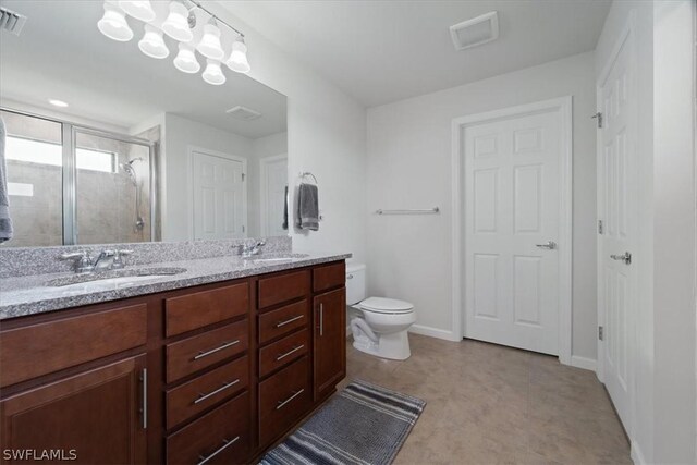 bathroom with double vanity, a stall shower, a sink, and toilet