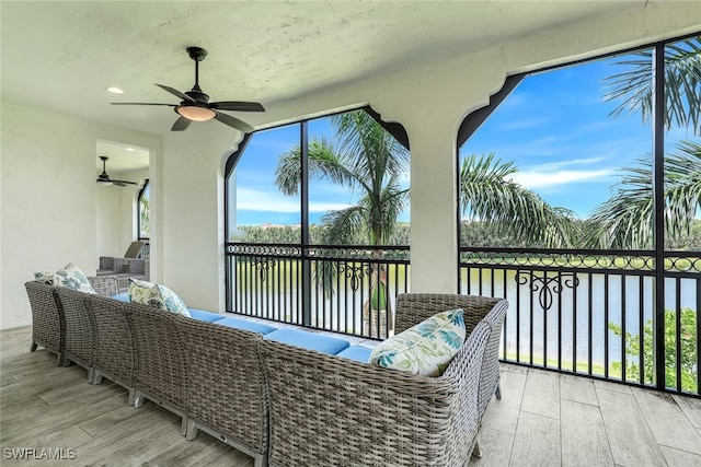 sunroom with ceiling fan and a water view