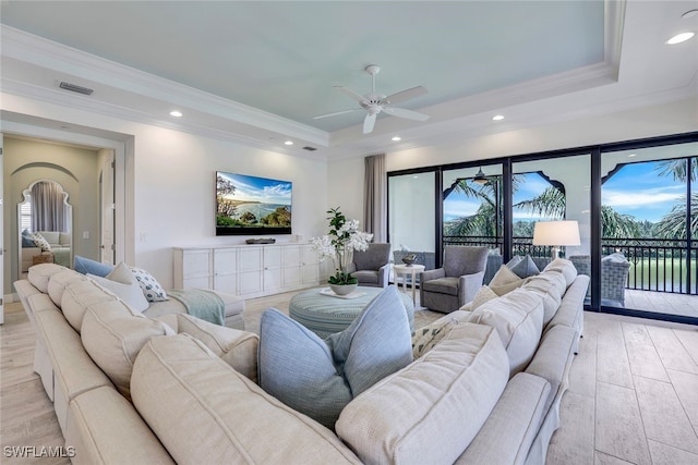 living room with crown molding, a wealth of natural light, light hardwood / wood-style floors, and a raised ceiling