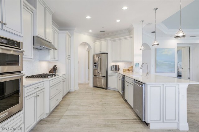 kitchen with appliances with stainless steel finishes, tasteful backsplash, decorative light fixtures, crown molding, and white cabinetry